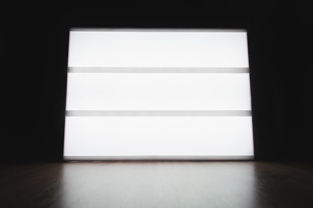 Foto caja de luz blanca con diseño personalizable sobre mesa de madera