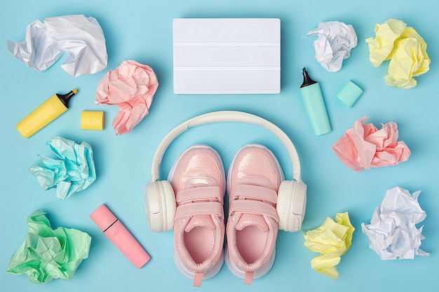 Caja de luz en blanco Auriculares zapatos rosas marcador de bolas de papel arrugado de color sobre fondo azul Concepto de educación Flat Lay Vista superior Still life Mock up Plantilla