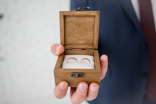 Caja de madera para anillos de boda en manos del novio