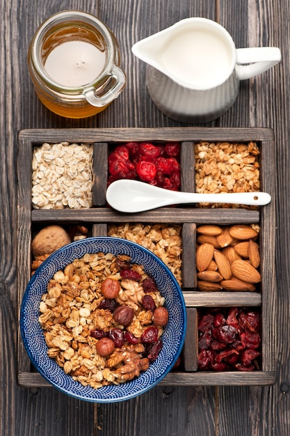 Caja de madera con artículos para el desayuno avena granola muesli nueces miel bayas secas y leche Vista superior