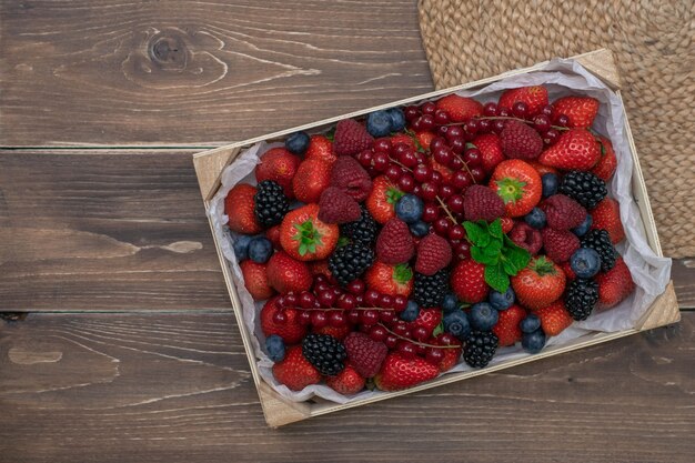 Caja de madera con bayas frescas en mesa de madera vintage. Moras frecas.