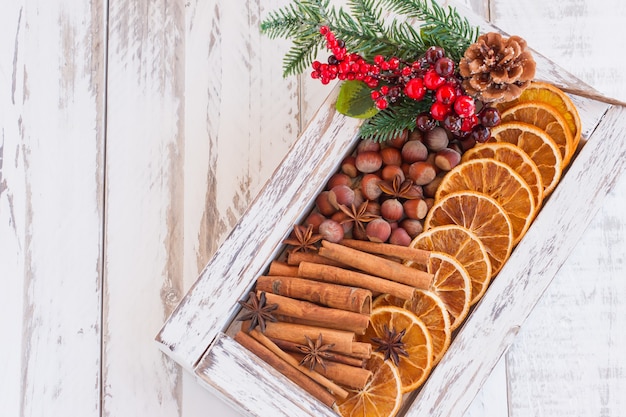 Caja de madera blanca con decoración orgánica de forrajes de invierno: rodajas de naranja secas, nueces, anís y nueces. Vista superior con espacio de copia.