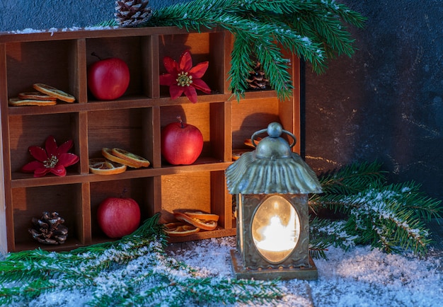 En una caja de madera, una decoración festiva de invierno: manzanas, rodajas de naranja, conos.