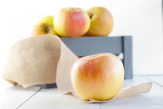 Caja de madera gris llena de manzanas frescas y aislada en un fondo blancoxA