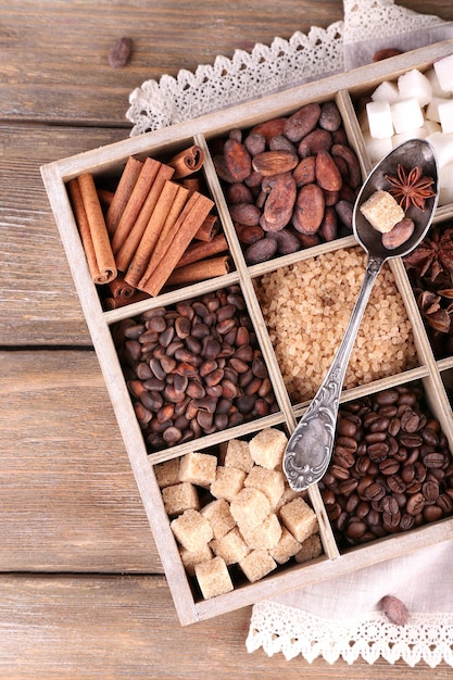 Caja de madera con un juego de terrones de azúcar de café y cacao, chocolate oscuro, canela y anís, primer plano sobre fondo de madera