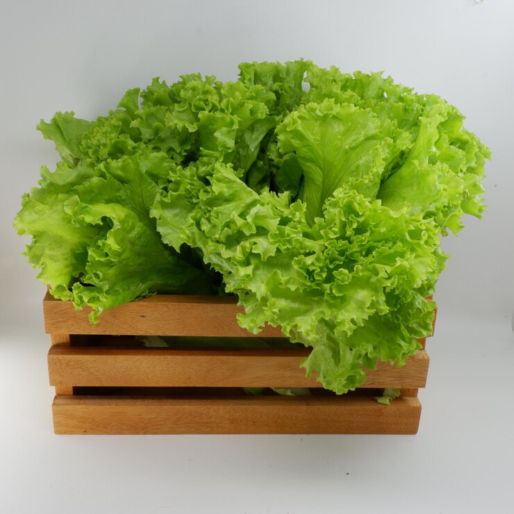 Foto una caja de madera con lechuga y una botella de agua al lado.