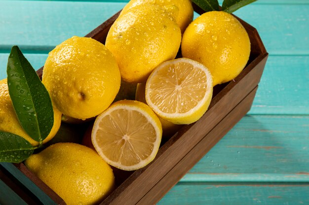 Caja de madera con limones sobre fondo de madera verde