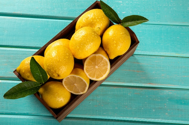 Caja de madera con limones sobre fondo de madera verde