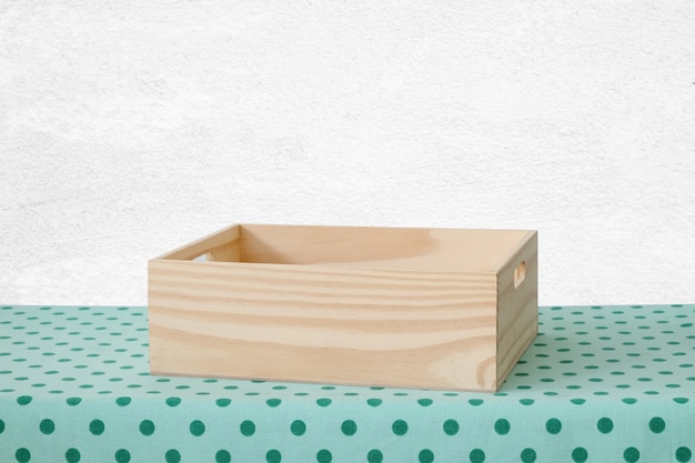 Caja de madera vacía en la mesa con fondo verde mantel lunares