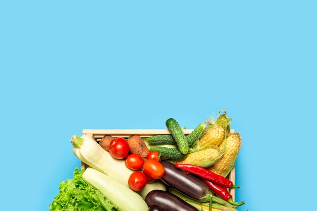 Caja de madera con verduras frescas sobre un fondo azul. Buen concepto de cosecha, producto natural. Vista plana, vista superior. Copia espacio