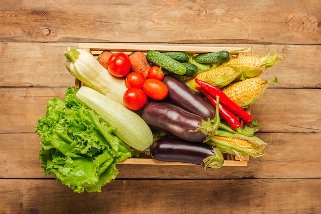 Caja de madera con verduras frescas sobre un fondo de madera.