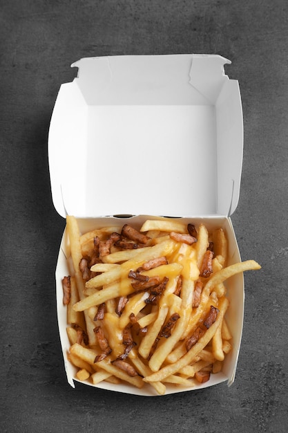 Caja con papas fritas y tocino en la mesa
