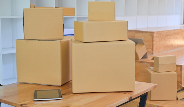 Caja de papel marrón y tableta en el escritorio en la tienda de la oficina, concepto de transporte de paquetes.