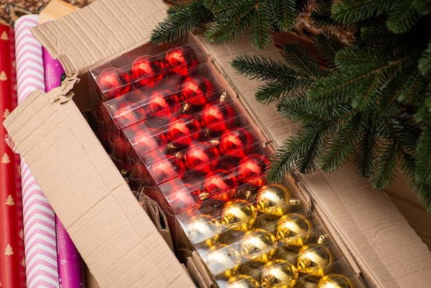 Caja de papel con papel de regalo de bolas de Navidad doradas y rojas cerca de Preparativos para decorar el árbol de Navidad