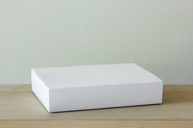 Caja de paquete de cartón blanco en blanco en mesa de madera