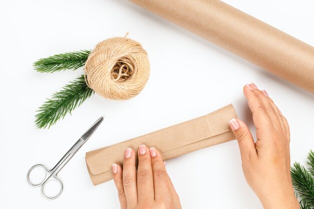 Caja de paquete de manos de mujer con regalo de año nuevo en papel marrón sobre fondo blanco aislado