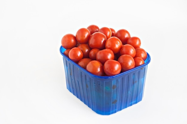 Caja de plástico azul llena de tomates aislados