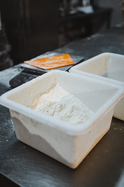 Caja de plástico con harina en polvo en la cocina de una panadería.