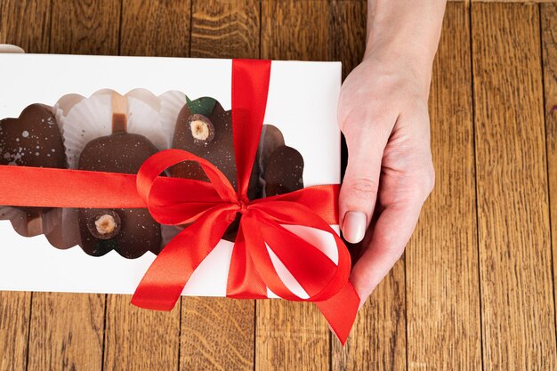 Caja de postres festivos con paletas de pastel de chocolate en manos femeninas vista recortada