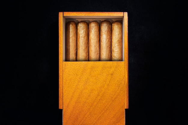 Caja de puros cubanos sobre una mesa negra en la oscuridad. Cigarros premium caros como regalo.