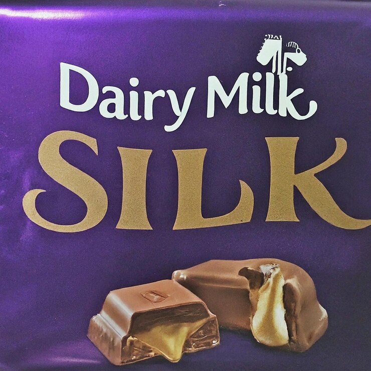 Foto una caja púrpura de chocolate de leche con una barra de chocolate en el fondo