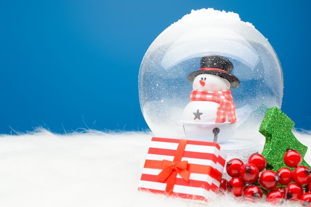 Caja de rayas con regalo de Navidad en arreglo con bola de nieve decorativa.