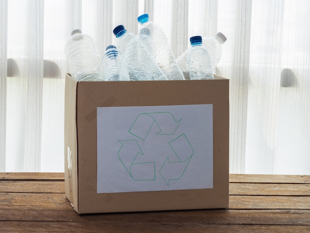 Caja de reciclaje llena de recipientes de plástico transparente.