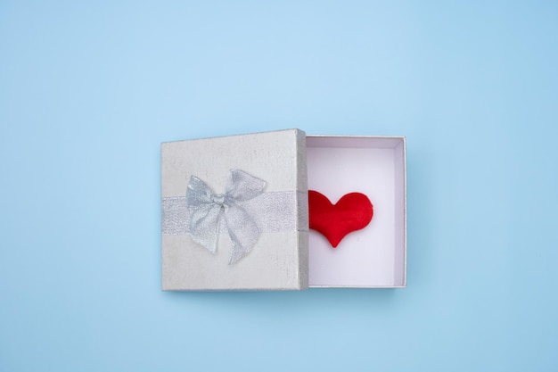 Caja de regalo abierta blanca simple aislada sobre fondo azul Corazón rojo en caja