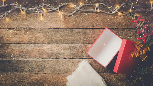 Caja de regalo abierta con iluminación navideña sobre fondo de madera rústica