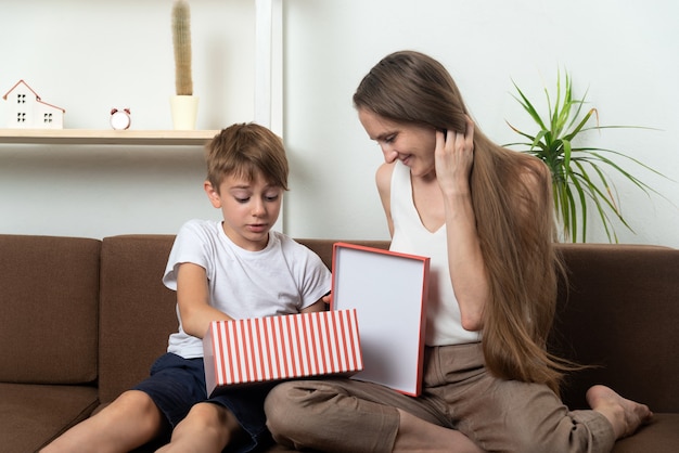 Caja de regalo abierta de mamá y niño. La madre le da un regalo a su hijo. Celebración familiar.