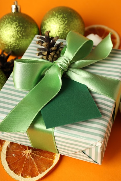 Foto caja de regalo y accesorios navideños sobre fondo naranja.