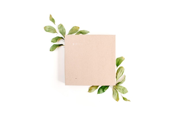 Caja de regalo artesanal y composición floral con hojas verdes