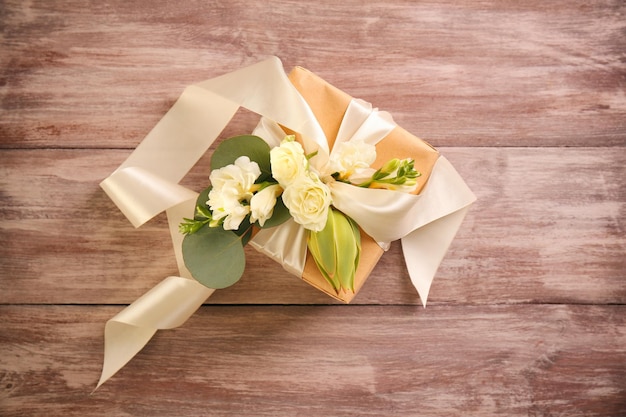 Caja de regalo artesanal con flores sobre mesa de madera