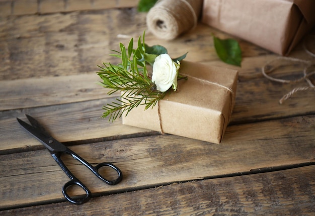 Caja de regalo artesanal con flores sobre mesa de madera