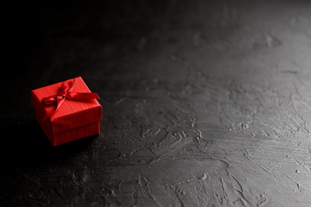 Caja de regalo artesanal sobre fondo negro, decorada con un lazo. Para cumpleaños, regalos de aniversario, postales de regalo.