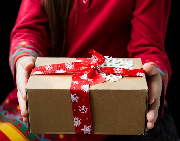 Caja de regalo atada con una cinta roja en las manos.