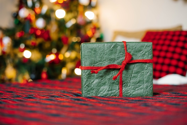 Caja de regalo atada con una cinta roja sobre luces navideñas