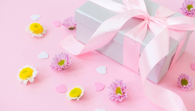 Caja de regalo atada con una cinta rosa sobre fondo rosa