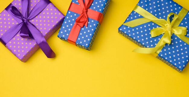 Caja de regalo atada con cinta de seda sobre un fondo amarillo, vista superior. Telón de fondo festivo, espacio de copia