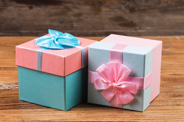 La caja de regalo ató la cinta roja con los pequeños corazones rojos impresos en él. Sobre fondo de madera vieja.