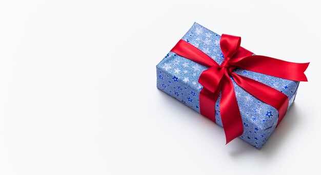 Caja de regalo azul con lazos rojos aislado sobre fondo blanco.