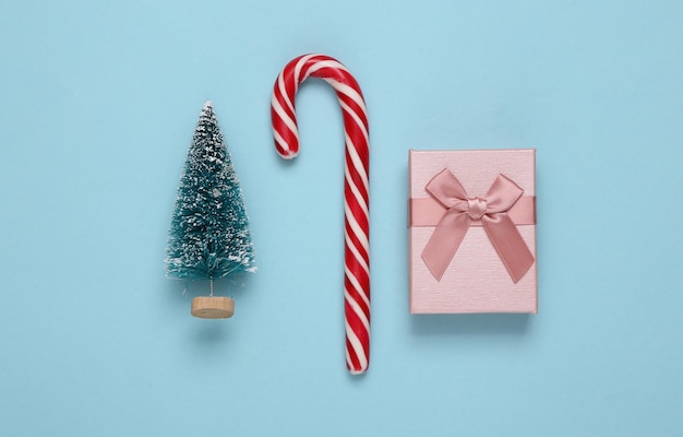Caja de regalo de bastón de caramelo a rayas de Navidad y mini árboles de Navidad sobre fondo azul Fondo de Navidad de año nuevo