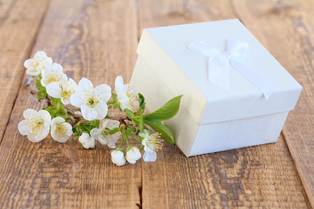 Caja de regalo blanca decorada con flores de jazmín sobre viejas tablas de madera.