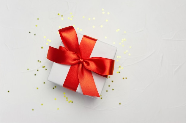 Caja de regalo blanca decorativa con un gran lazo rojo con estrellitas doradas.