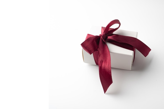 Caja de regalo blanca con lazo rojo en fondo blanco con corazones rojos bandera de vacaciones vista superior Feliz día de San Valentín