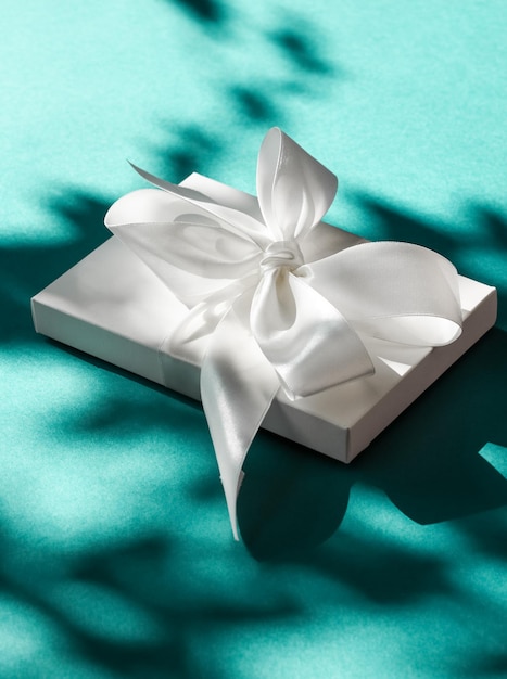 Caja de regalo blanca de vacaciones de lujo con cinta de seda y lazo sobre fondo verde esmeralda boda de lujo o regalo de cumpleaños