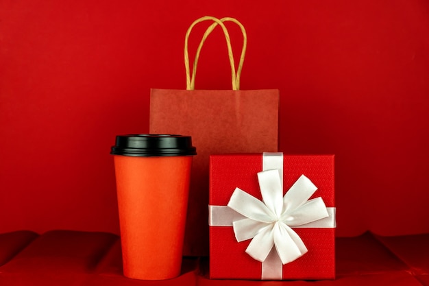 Foto caja de regalo, bolsa de papel y taza de café en la habitación roja