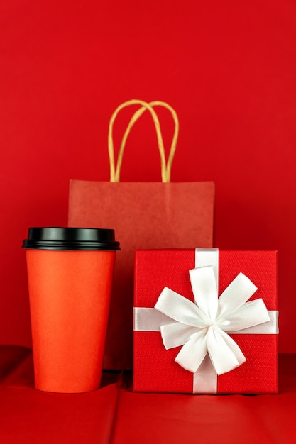 Foto caja de regalo, bolsa de papel y taza de café en la habitación roja