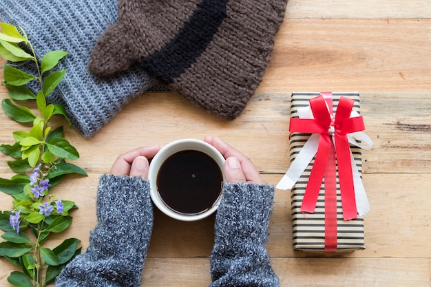 Caja de regalo con bufanda de lana tejida, gorro y mano de mujer.