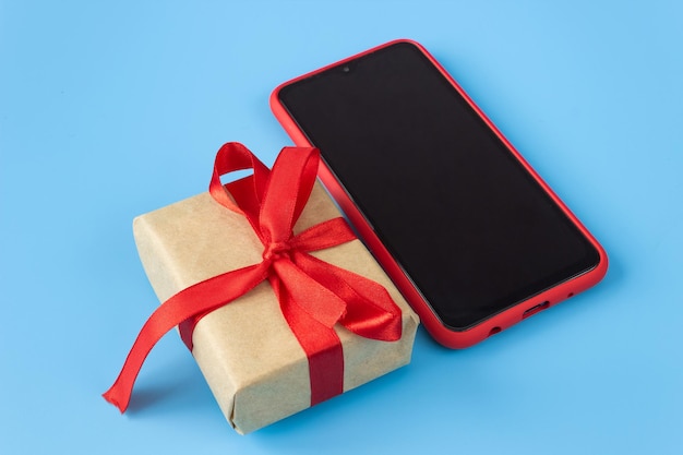 Caja de regalo con burocracia con un smartphone en un fondo azul. Concepto de vacaciones y ventas.